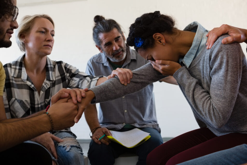 Femme qui pleure entourée de personnes qui la réconfortent